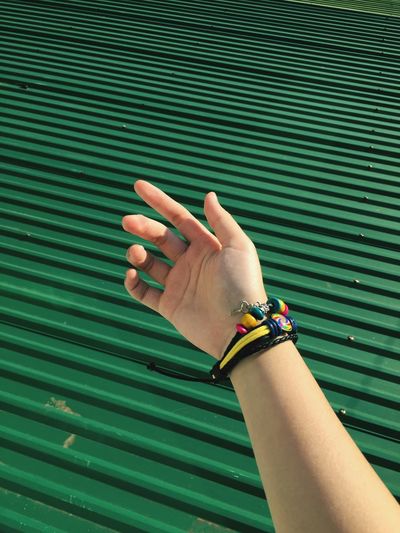Cropped hand by green corrugated iron