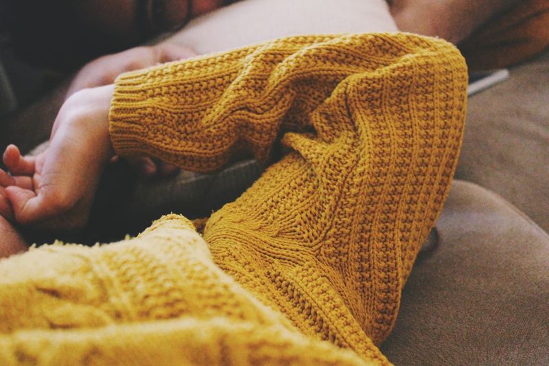 Close-up of person wearing sweater lying on sofa