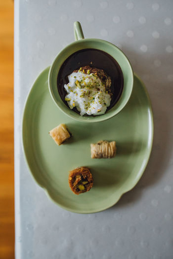 Drinking chocolate with pistachios in green cup and plate with assorted baklava desserts
