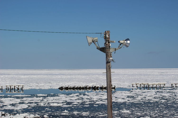View of wooden pole on sea against clear sky