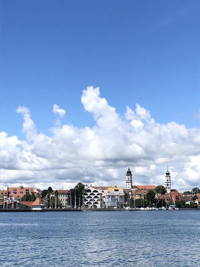 Buildings at waterfront against cloudy sky