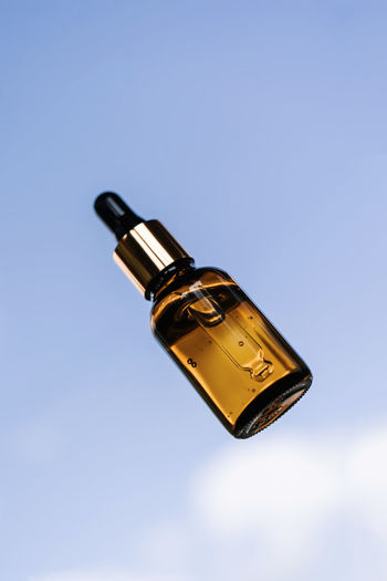 Low angle view of yellow bottle against blue sky