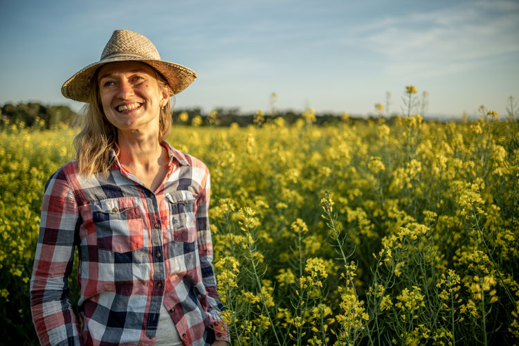 Ortrait of a girl smiling in a rapeseed field at sunset