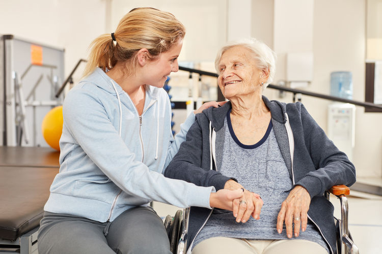 Smiling nurse consoling senior woman at nursing home