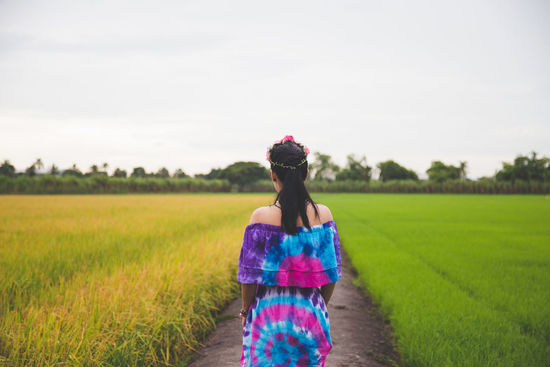 Rear view of woman standing on field against sky