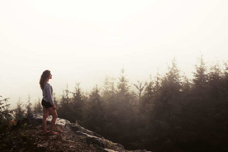 Outdoorsy woman looks at the view from the summit of a mountain
