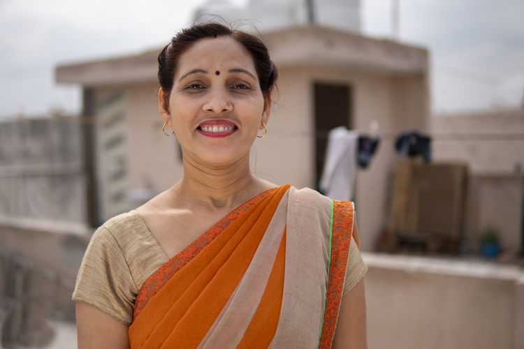 Portrait of cheerful woman in sari standing on terrace