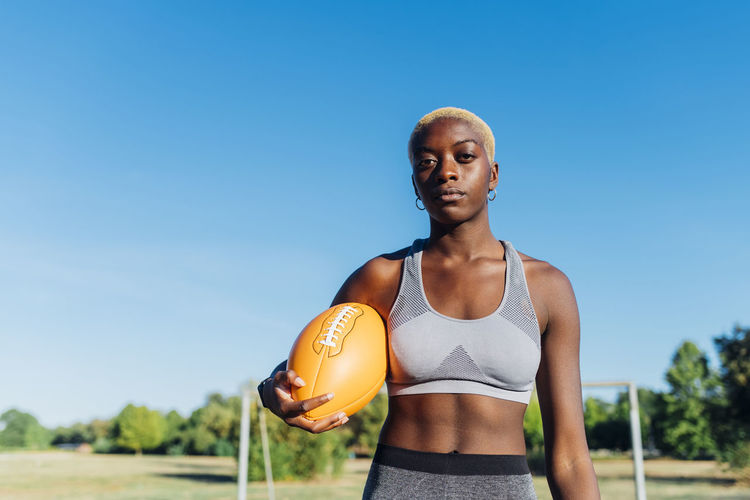 Young american football player with ball on sunny day