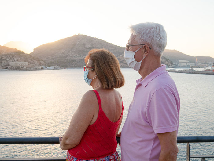 Caucasian elderly couple with face mask looking at the sea after a rel