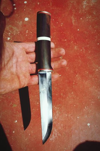 Cropped image of man holding knife against table