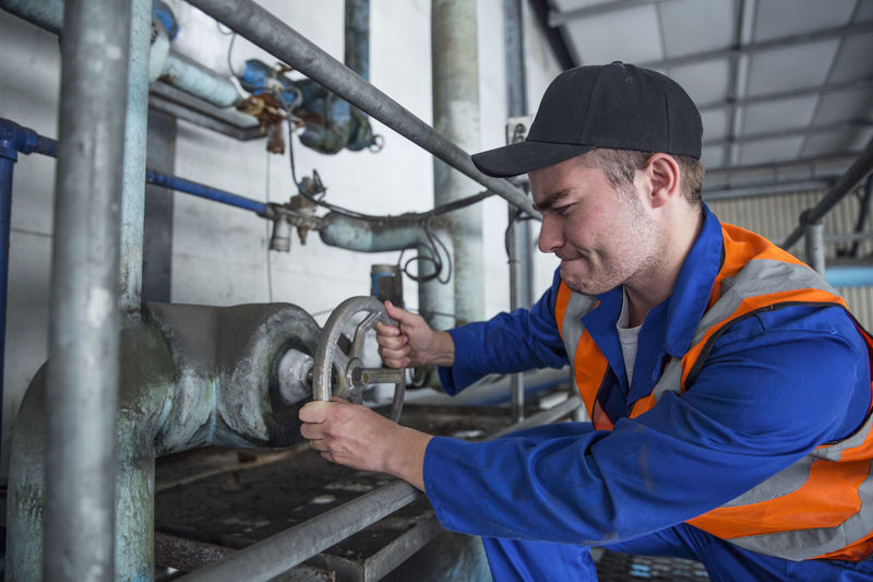 Worker turning valve in factory