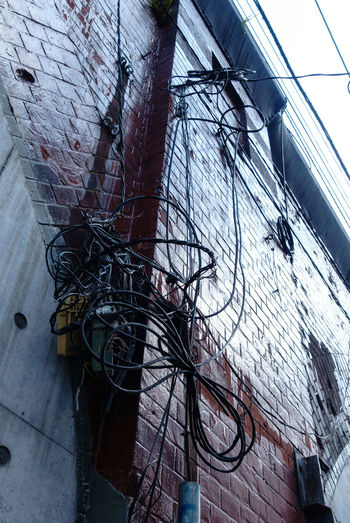 Low angle view of cables against buildings