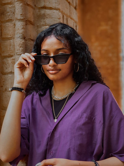 Portrait of woman wearing sunglasses against wall