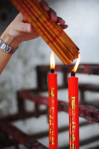 Close-up of hand holding lit candles in temple