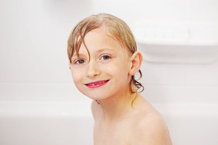 Portrait of smiling wet boy in bathtub