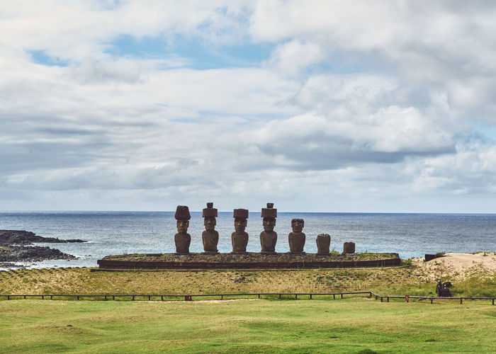 Moai statues on beach by sea against sky