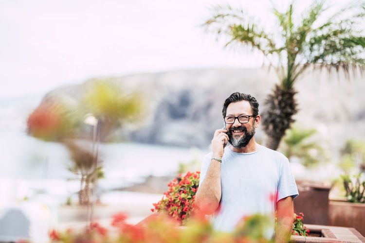 Smiling man talking on phone while looking away outdoors