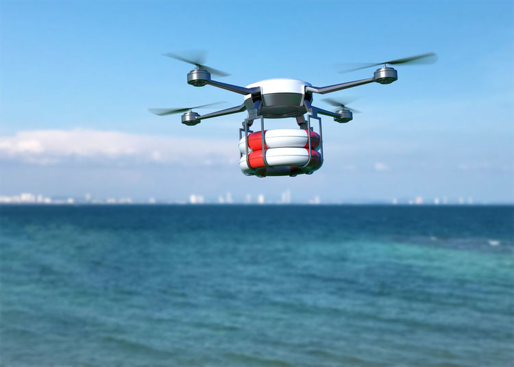 Drone flying over sea against sky