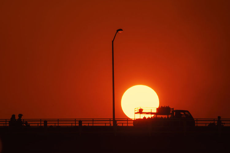 Silhouette bridge against orange sky during sunset