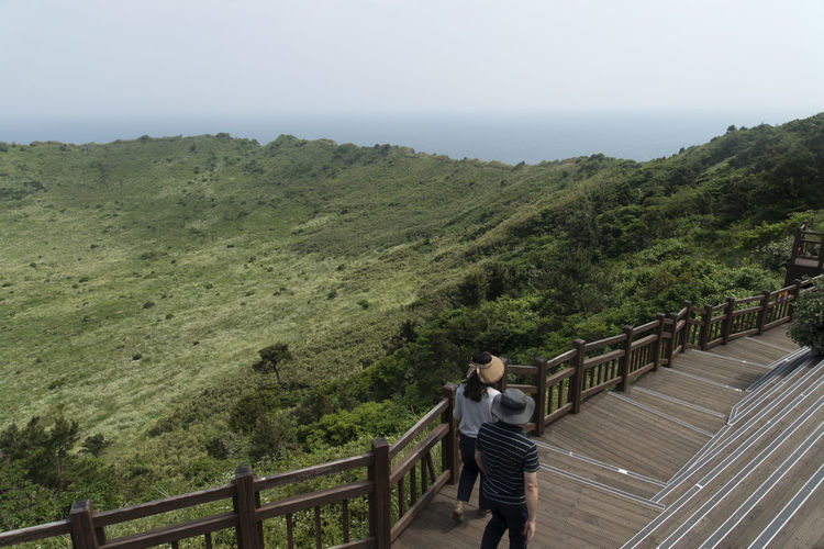 High angle view of friends walking on steps at seongsan ilchulbong against sky