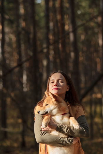 Beautiful woman walking shiba inu dog in fall forest. autumn mood