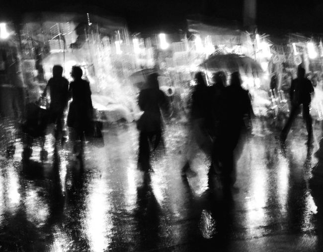 Silhouette people walking on wet street at night