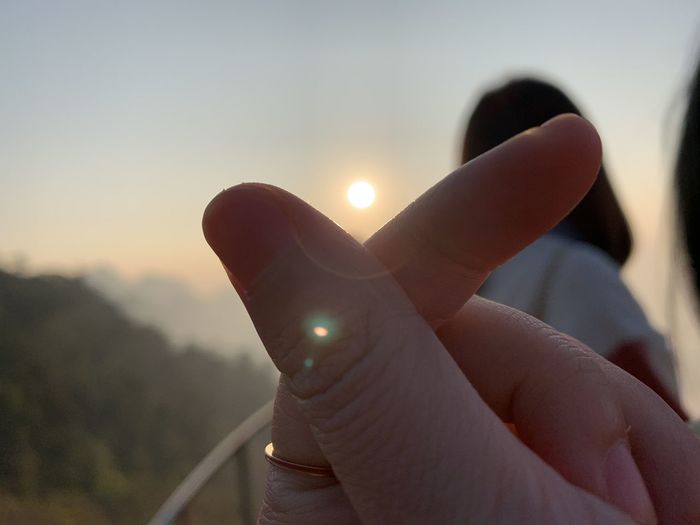 Close-up of hand holding sun during sunset