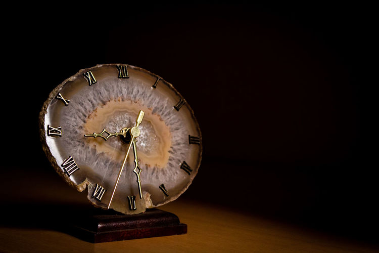Close-up of clock on table against black background