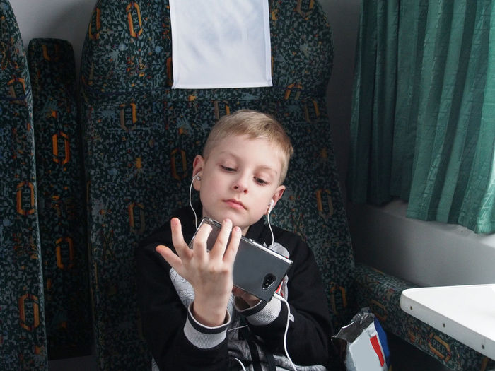 Boy listening to music through in-ear headphones in train