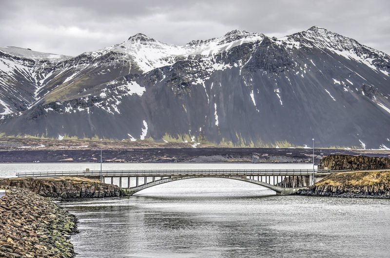 Bridge over snowcapped mountains against sky