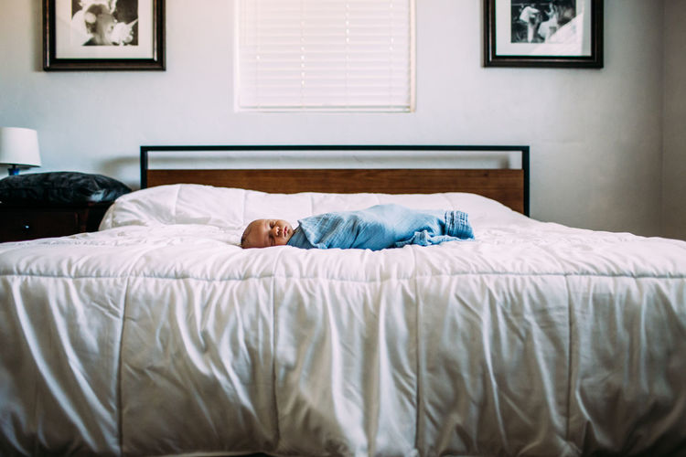 Newborn sleeping alone on large bed