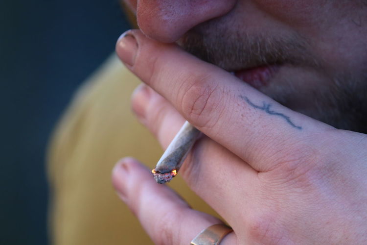 Close-up of young man smoking marijuana joint