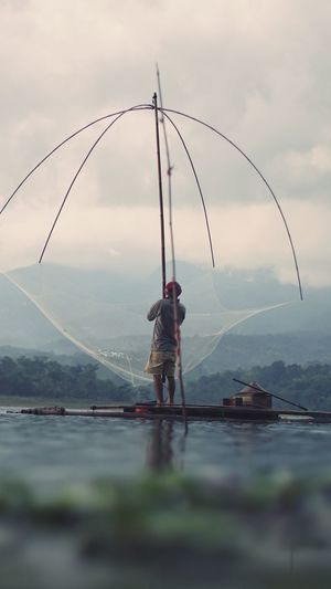 Rear view of man fishing against sky