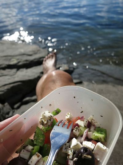 Close-up of person holding food by beach