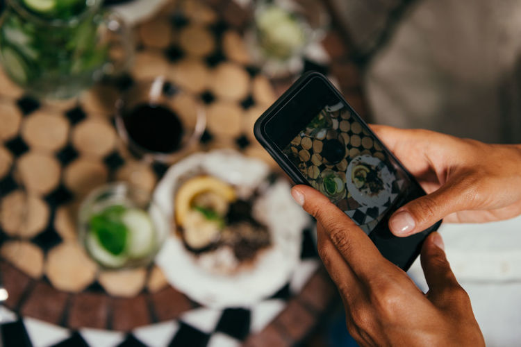 Cropped hand of woman photographing food on smart phone