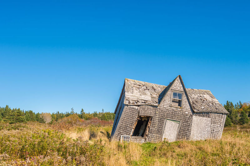 House on field against clear blue sky
