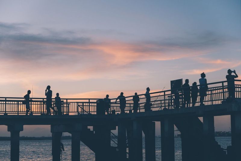 Silhouette people on bridge over river
