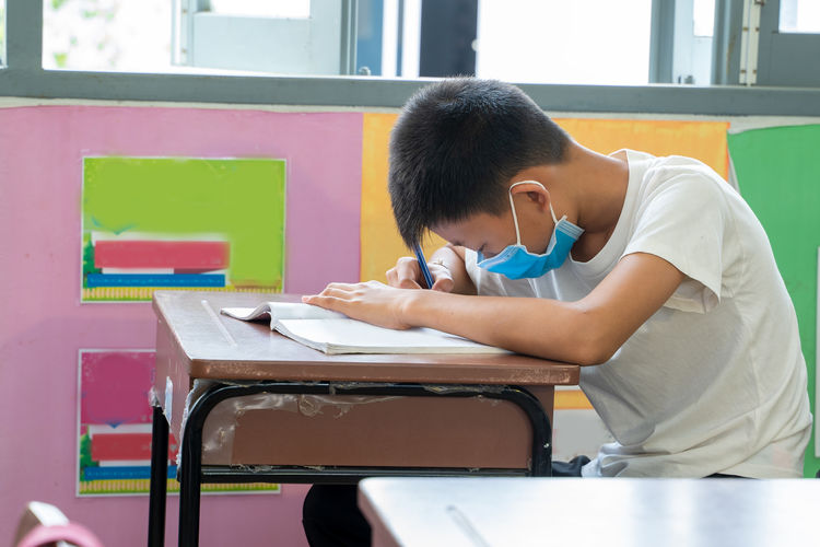 Asian elementary school wear mask for protect corona virus desk