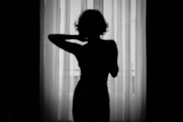 Sensuous woman posing against curtain in room