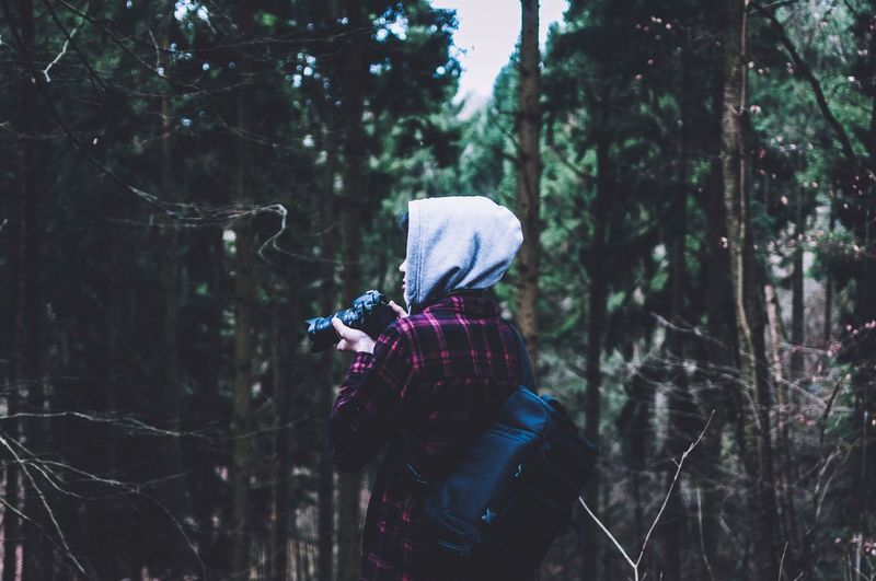 Rear view of woman photographing in forest