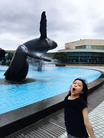 Portrait of girl screaming by fountain against sky