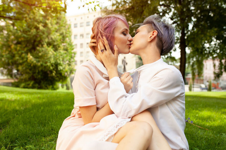 Young lesbians kissing while sitting in park