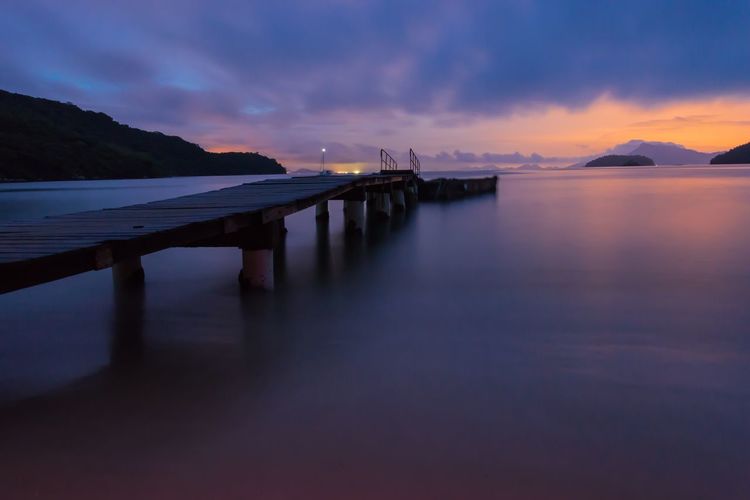 Pier over sea against dramatic sky