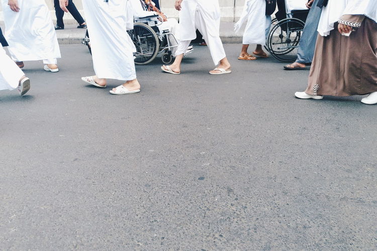 Low section of people walking on road in city