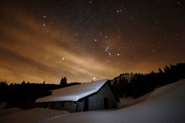 Exterior of house on landscape against star field during winter