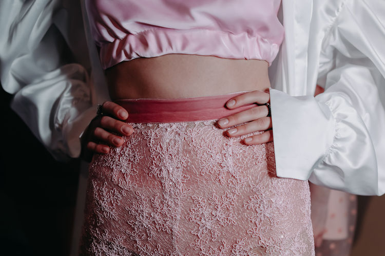 Cropped figure of model wearing pink and white fashion stylish outfit