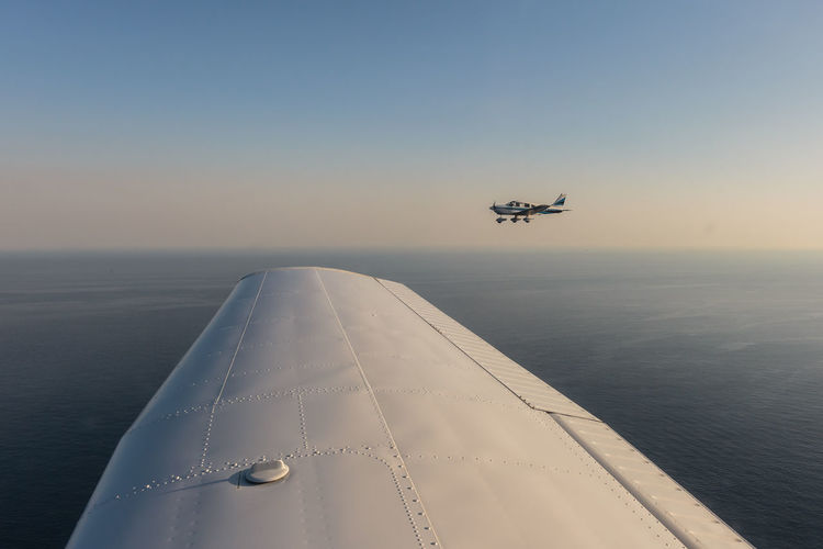 Airplane flying over sea against clear sky