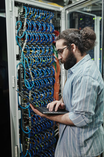 Technician configuring server through laptop in server room