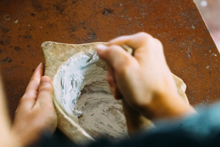 Cropped hands of woman making medicine using mortar and pestle on table