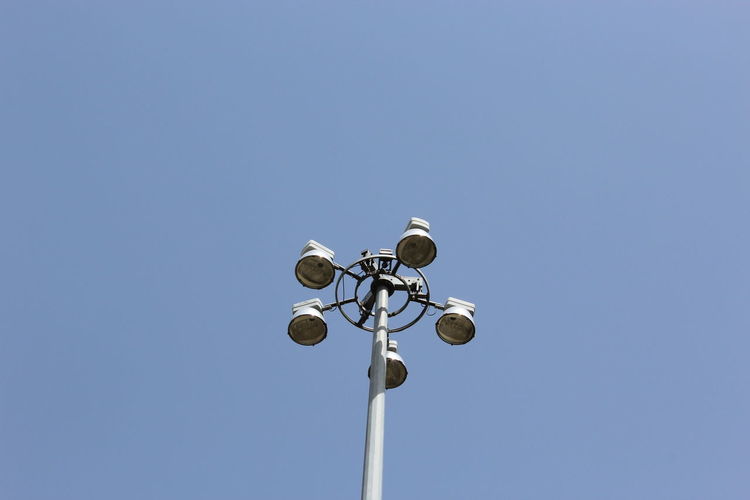 Low angle view of street lights against clear blue sky